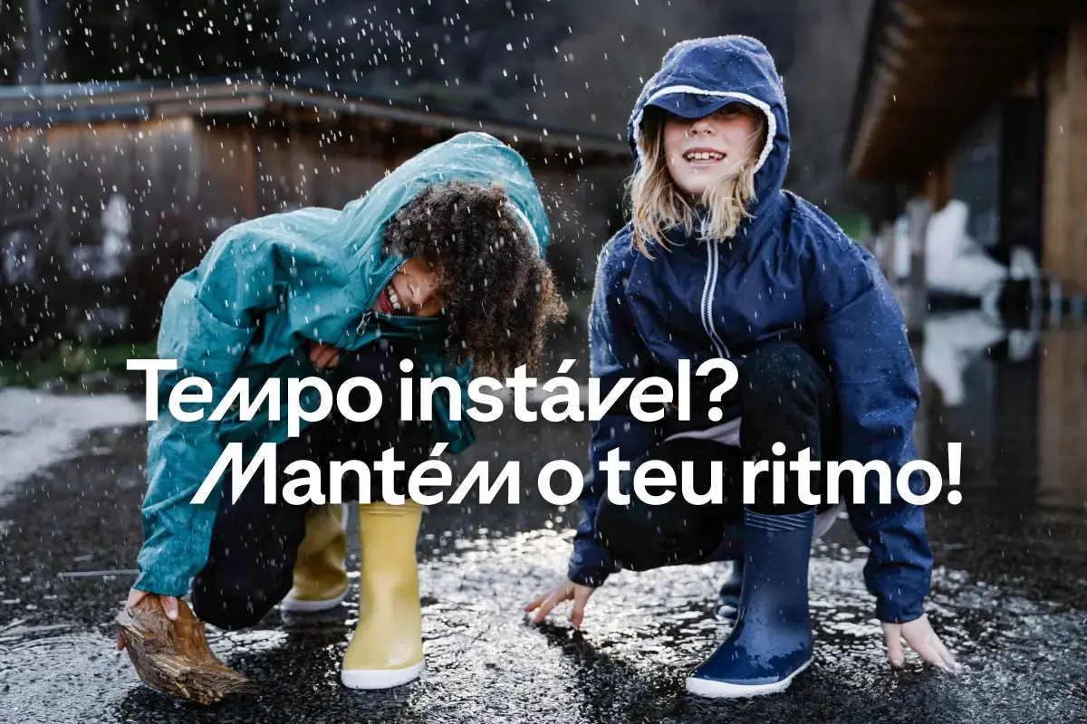 Crianças com impermeáveis e galochas infantis à chuva, com o texto: Tempo instável? Mantém o teu ritmo!