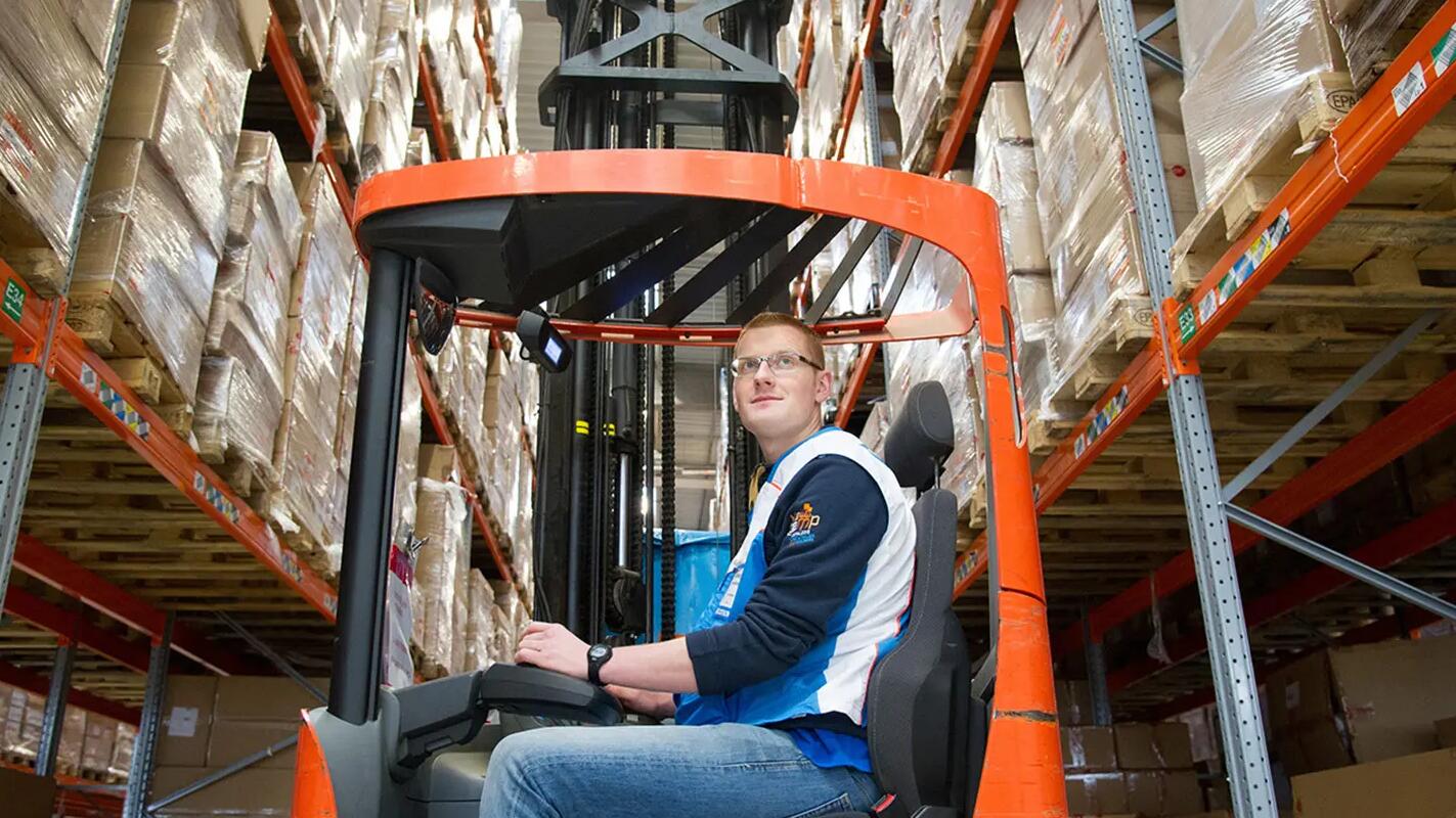 In the picture, a DECATHLON teammate handling a heavy load using a forklift.