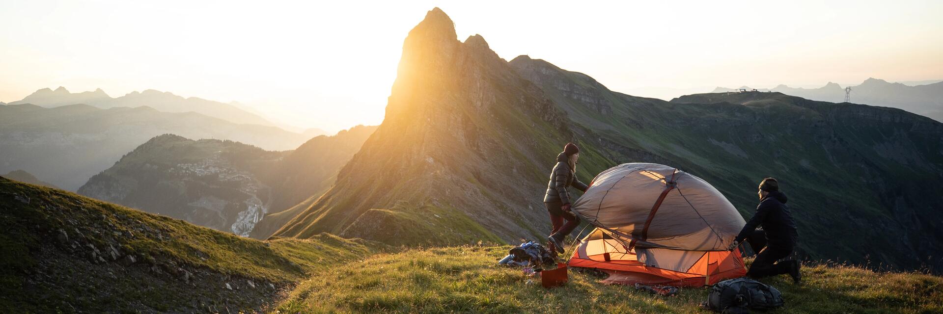 Zwei Bergsteiger bauen ein Zelt auf vor Bergkulisse. Überschrift der Landingpage lautet Retoure.