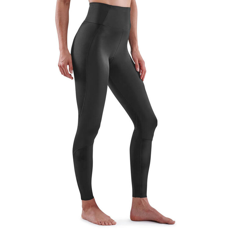 Women's black slim-fit gym tights with a high-rise waistband and full-length legs, styled with a cropped top and trainers