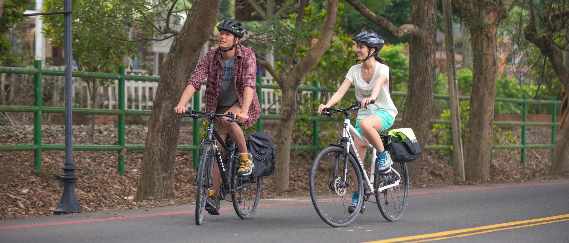 Kobieta i mężczyzna jadący w kaskach na rowerach przez miasto