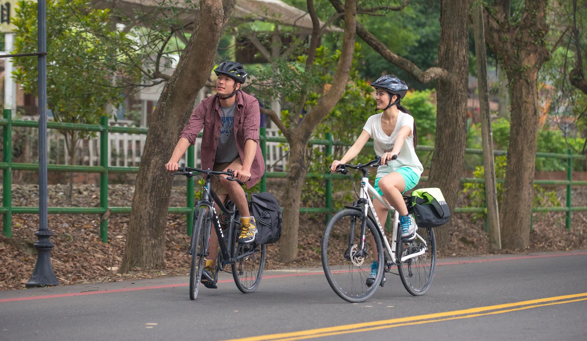kobieta i mężczyzna w kaskach rowerowych jadący rowerami po ulicy 
