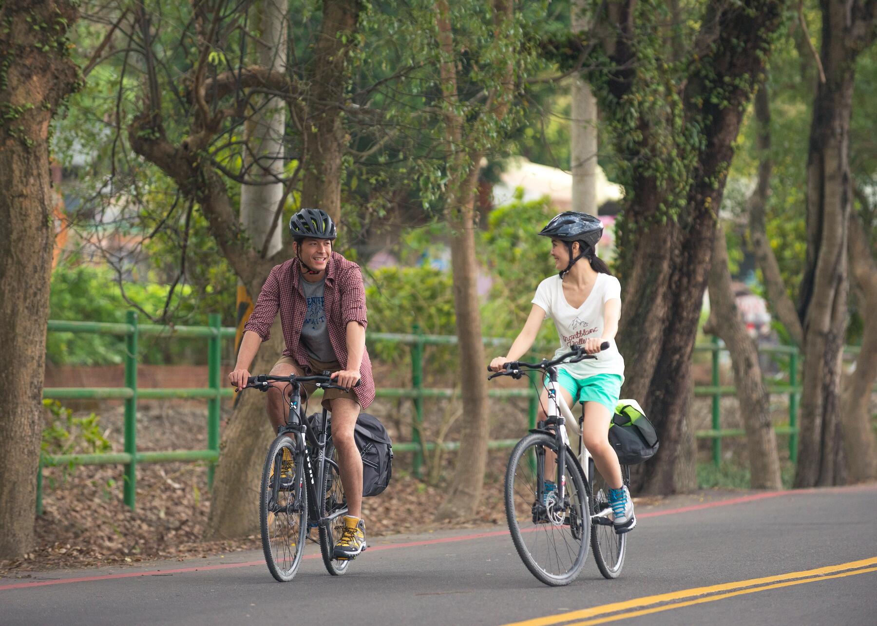 mężczyzna i kobieta w kaskach rowerowych jadący na rowerach
