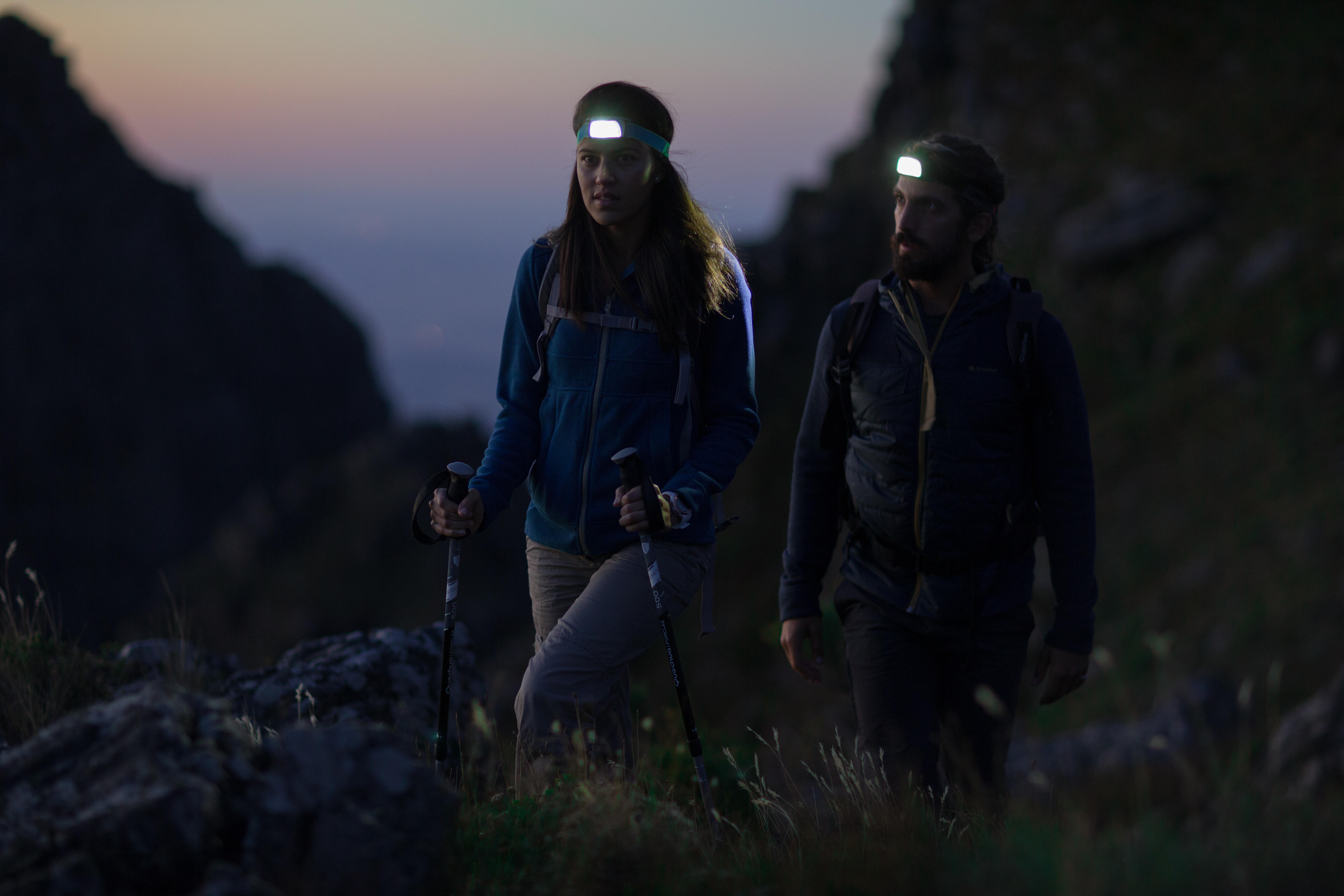 Two hikers wearing head torches while walking at dusk
