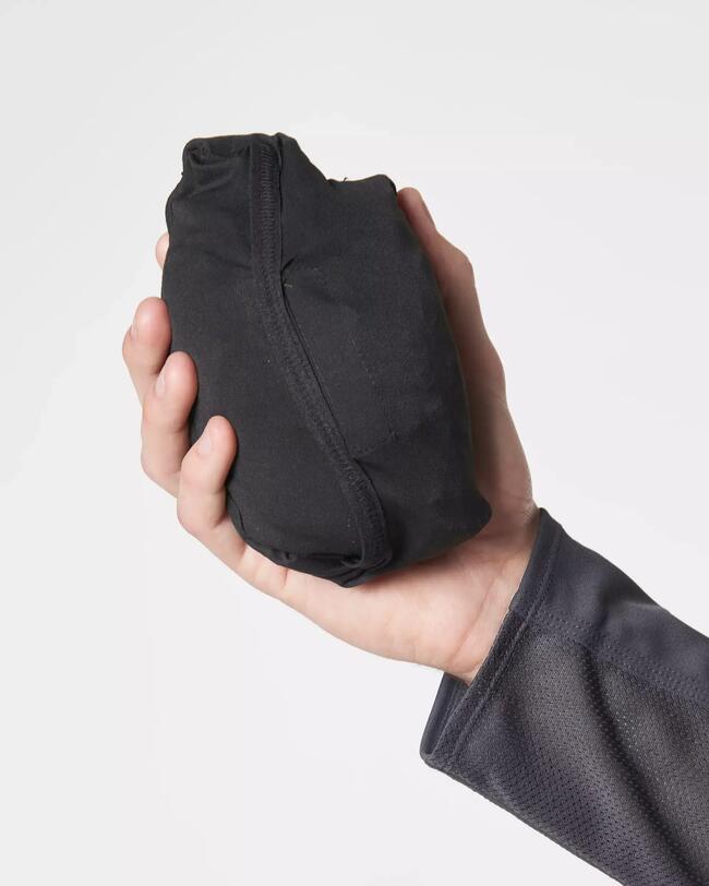 Schwarze Laufhose in kompakter Tasche, glatte Oberfläche, von Hand gehalten.