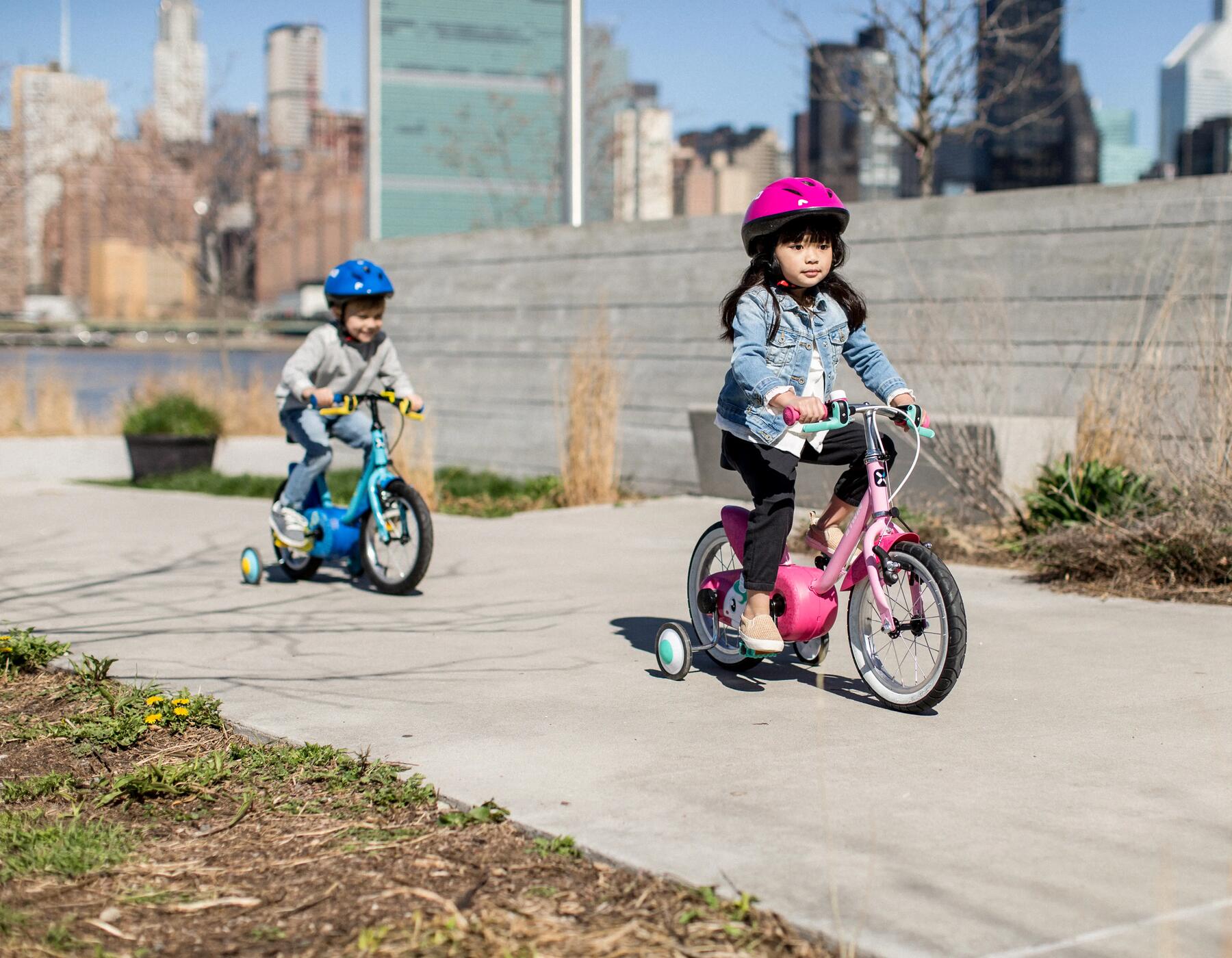 dzieci w laskach jadące na rowerach z dodatkowymi kółkami