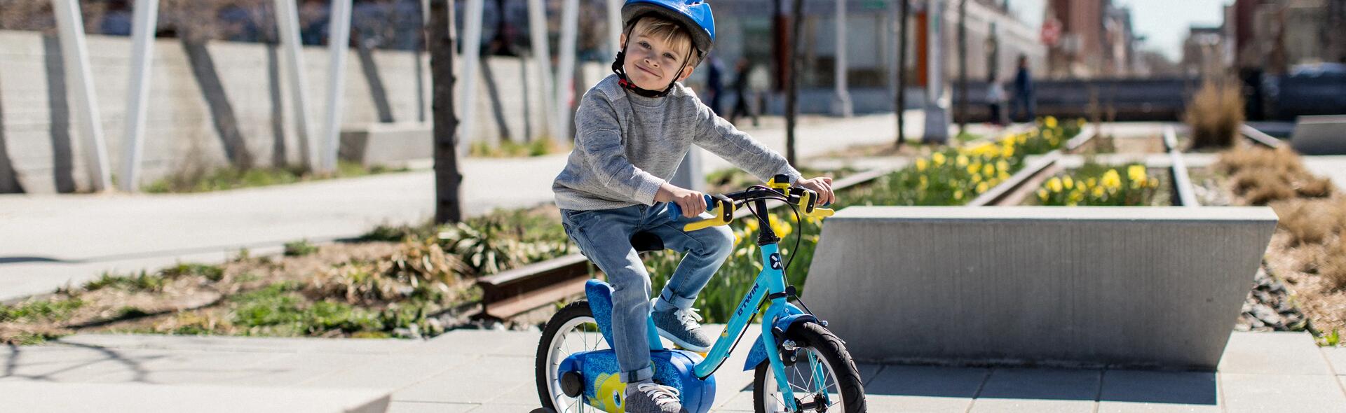 chłopiec jadący na rowerze z dodatkowymi kółkami 