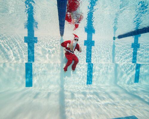 un père Noël sous l'eau dans une piscine olympique