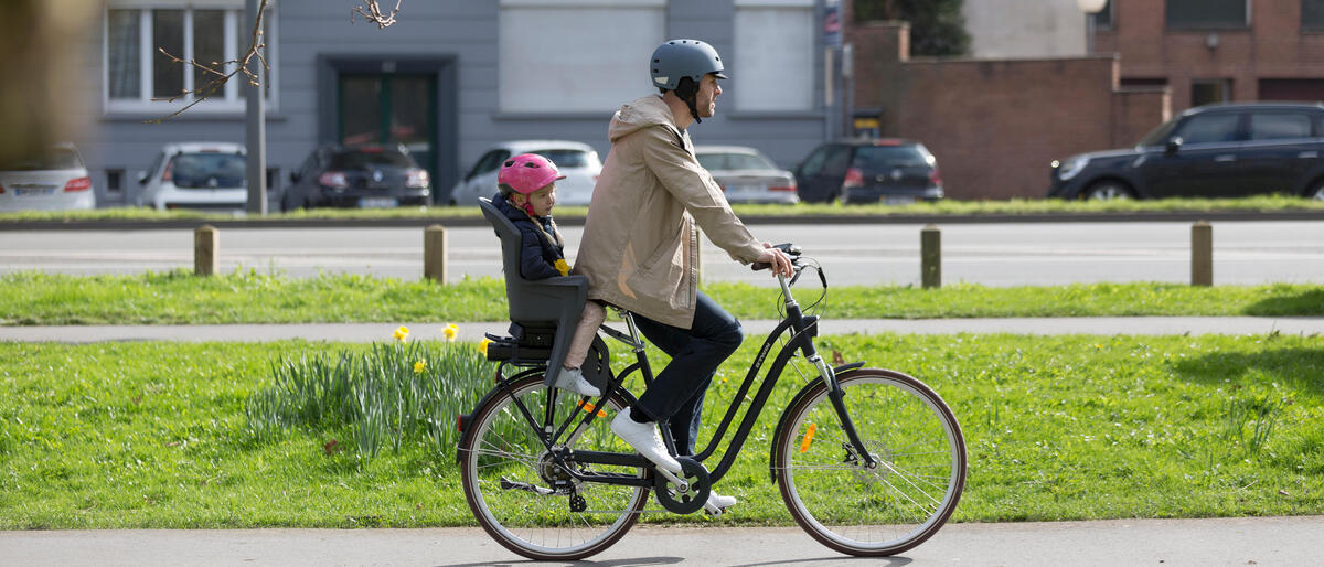 homem a andar de bicicleta com crianca na cadeira