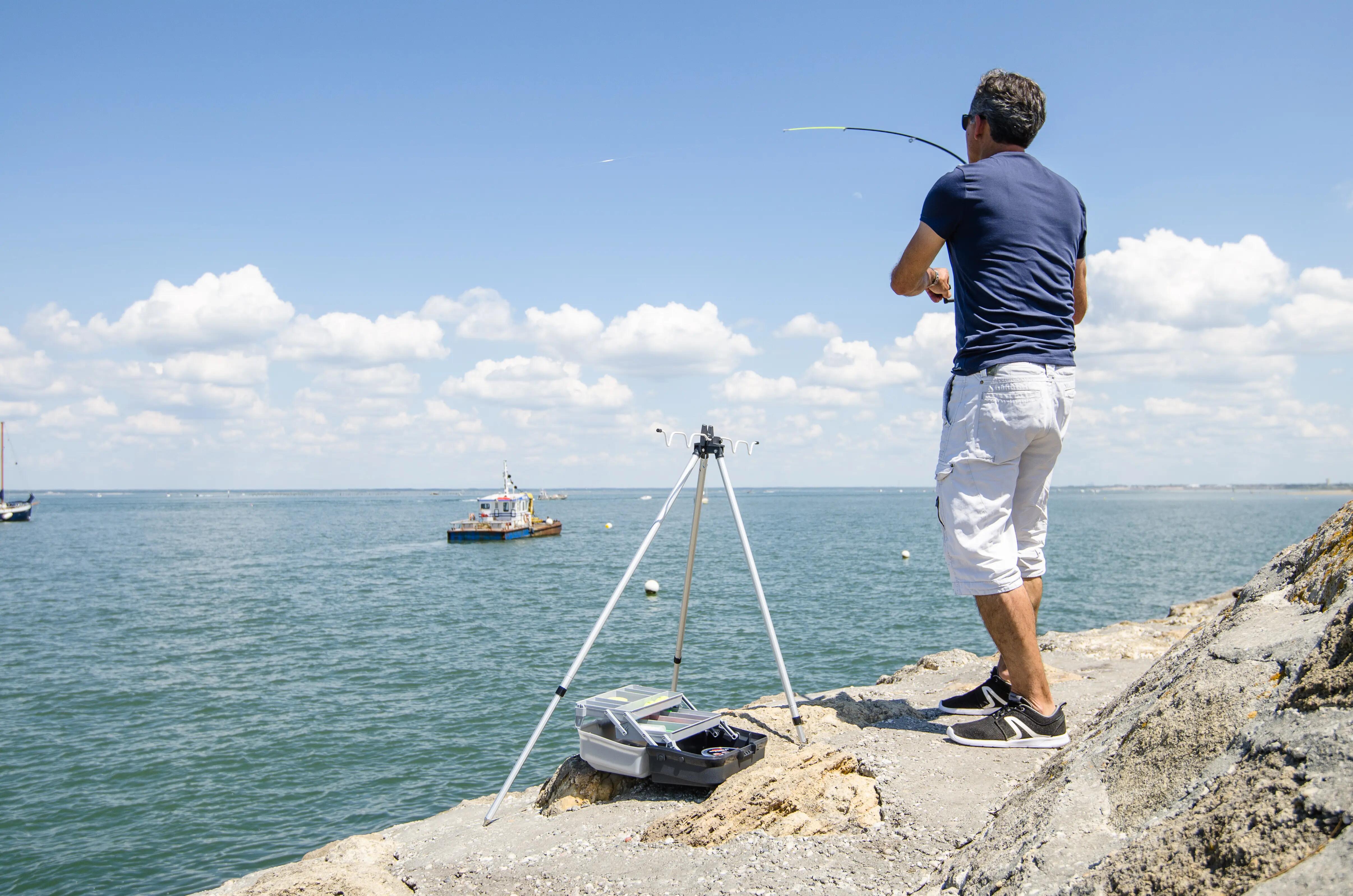 Angler casting a fishing rod from a rocky shoreline
