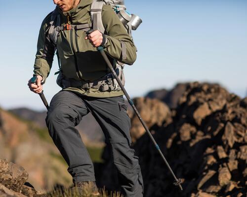 mężczyzna wędrujący w spodniach trekkingowych z kijami trekkingowymi w rękach