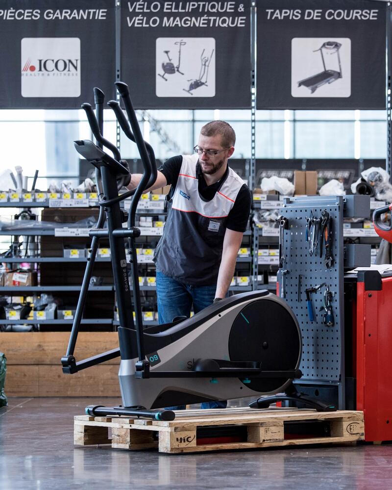 Ein Decathlon-Mitarbeiter steht mit einem Hometrainer in der Werkstatt