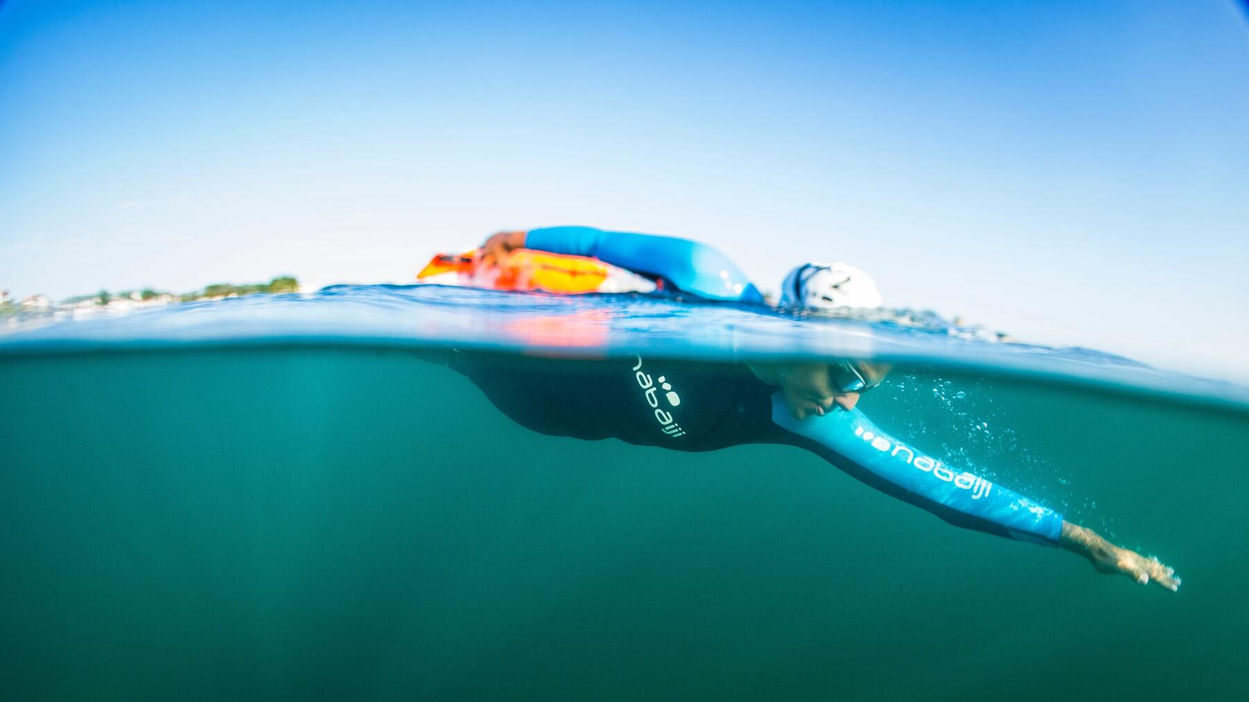 Eine Person schwimmt im Meer in Neoprenanzug