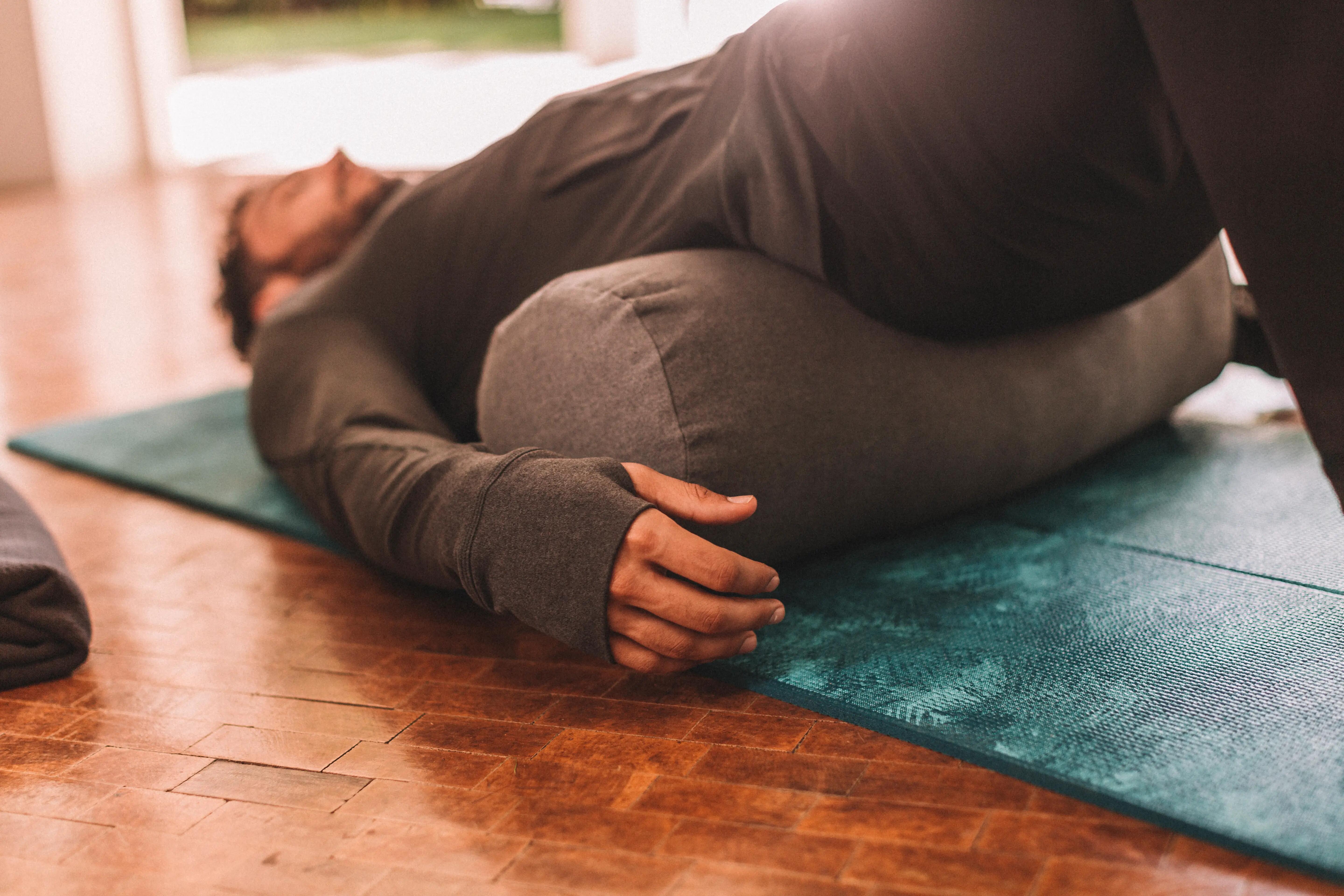 Person wearing long-sleeve yoga clothes during a restorative yoga pose