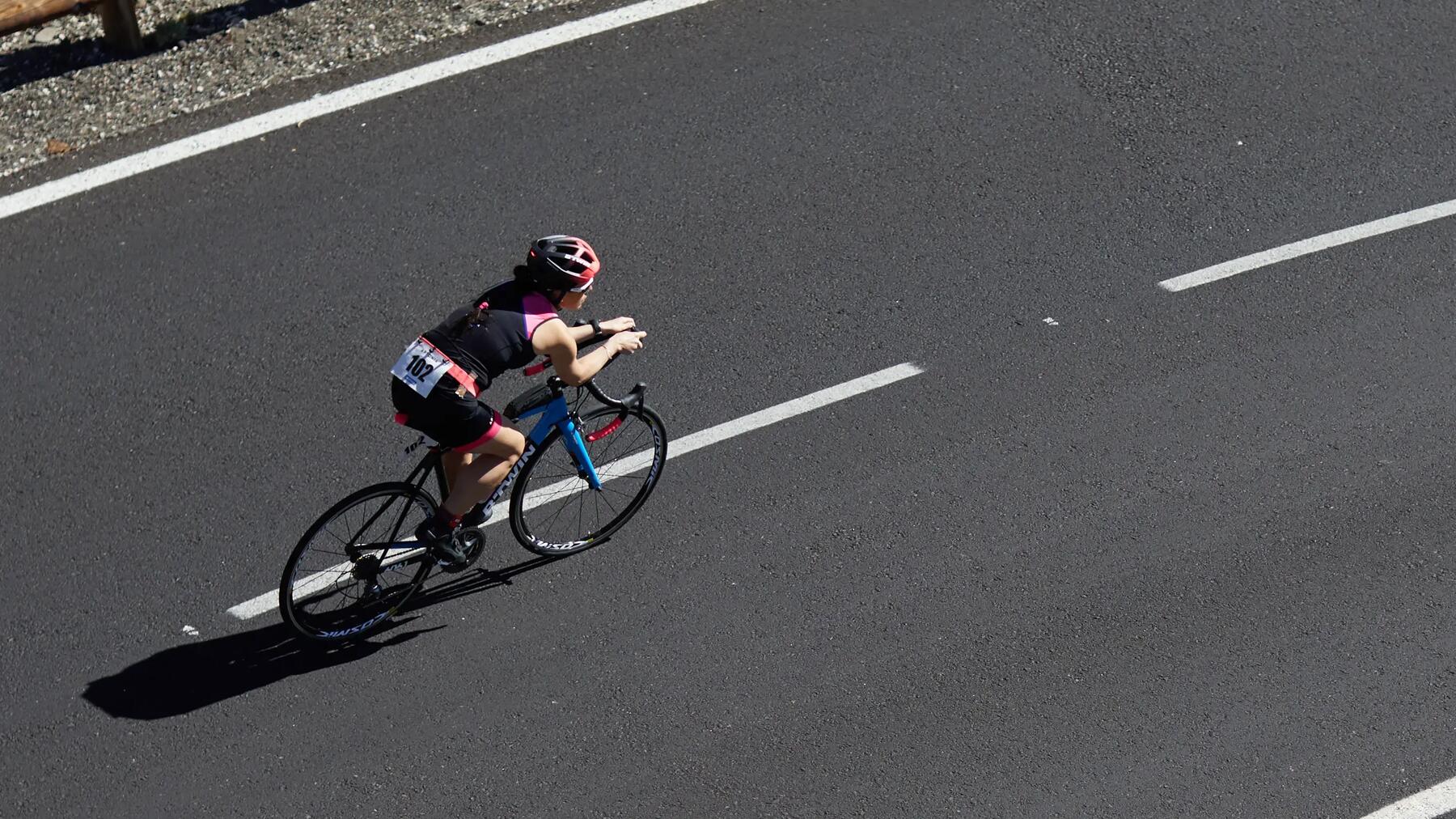 Kobieta w kasku jadąca rowerem triathlonowym w maratonie