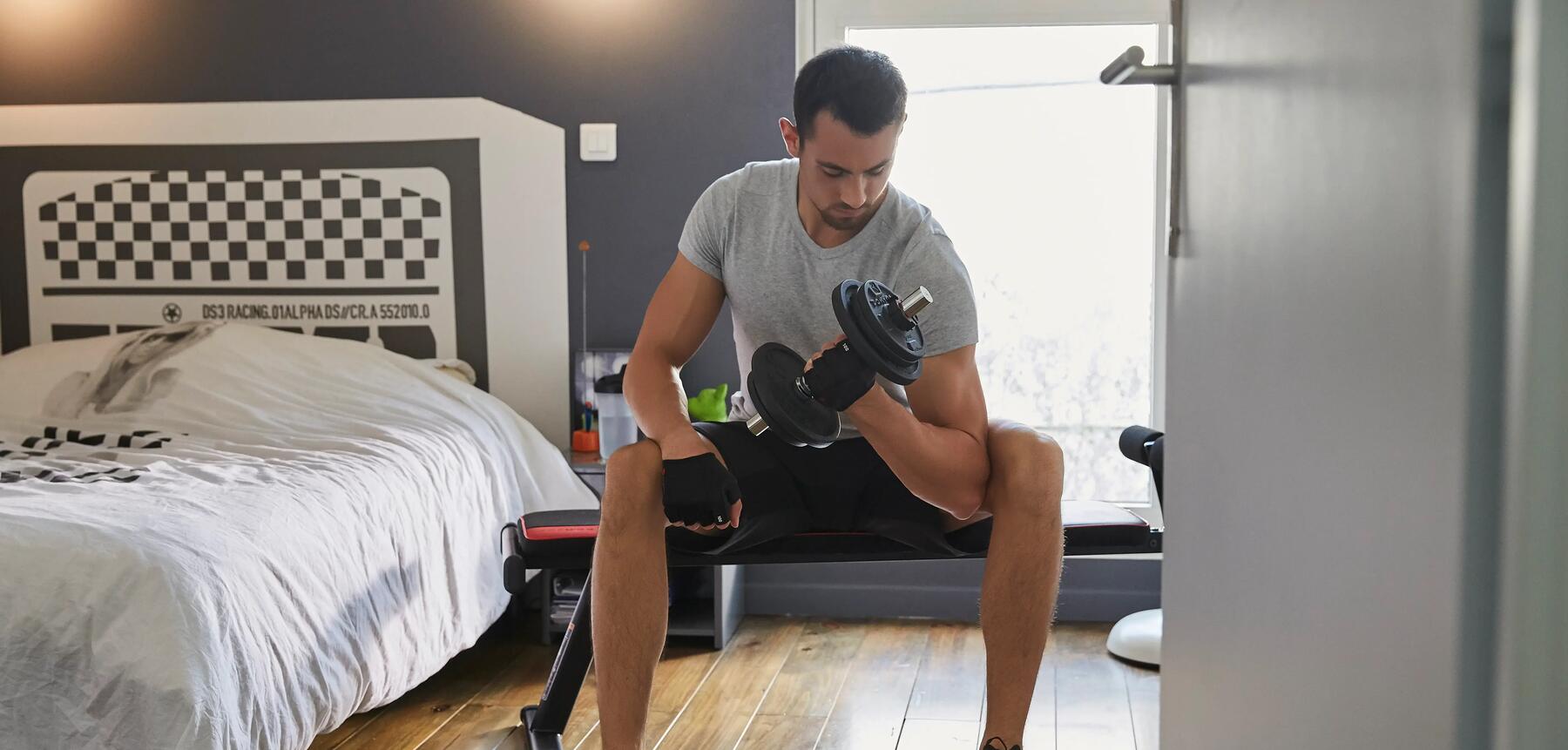 A man working out with a dumbbell in his bedroom