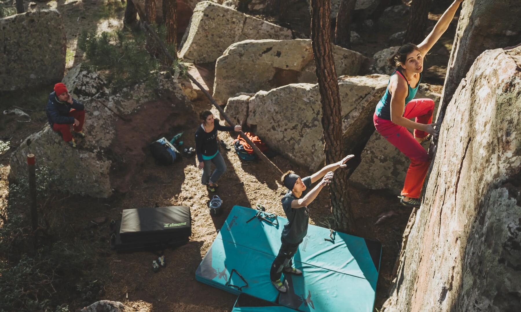 a group climbing with a blue crash pad on the ground