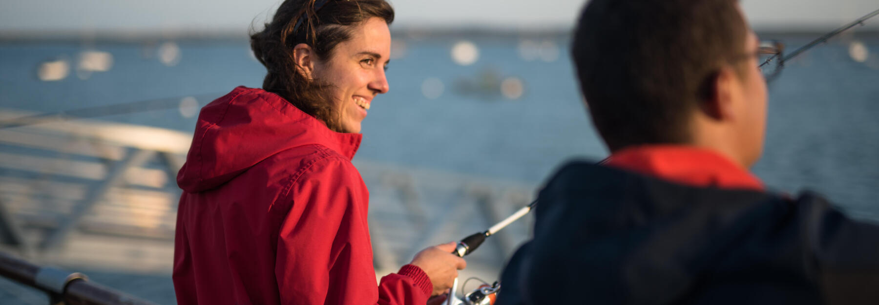 femme sur le quai en ville qui sourit en regardant les gens qui pêchent avec elle