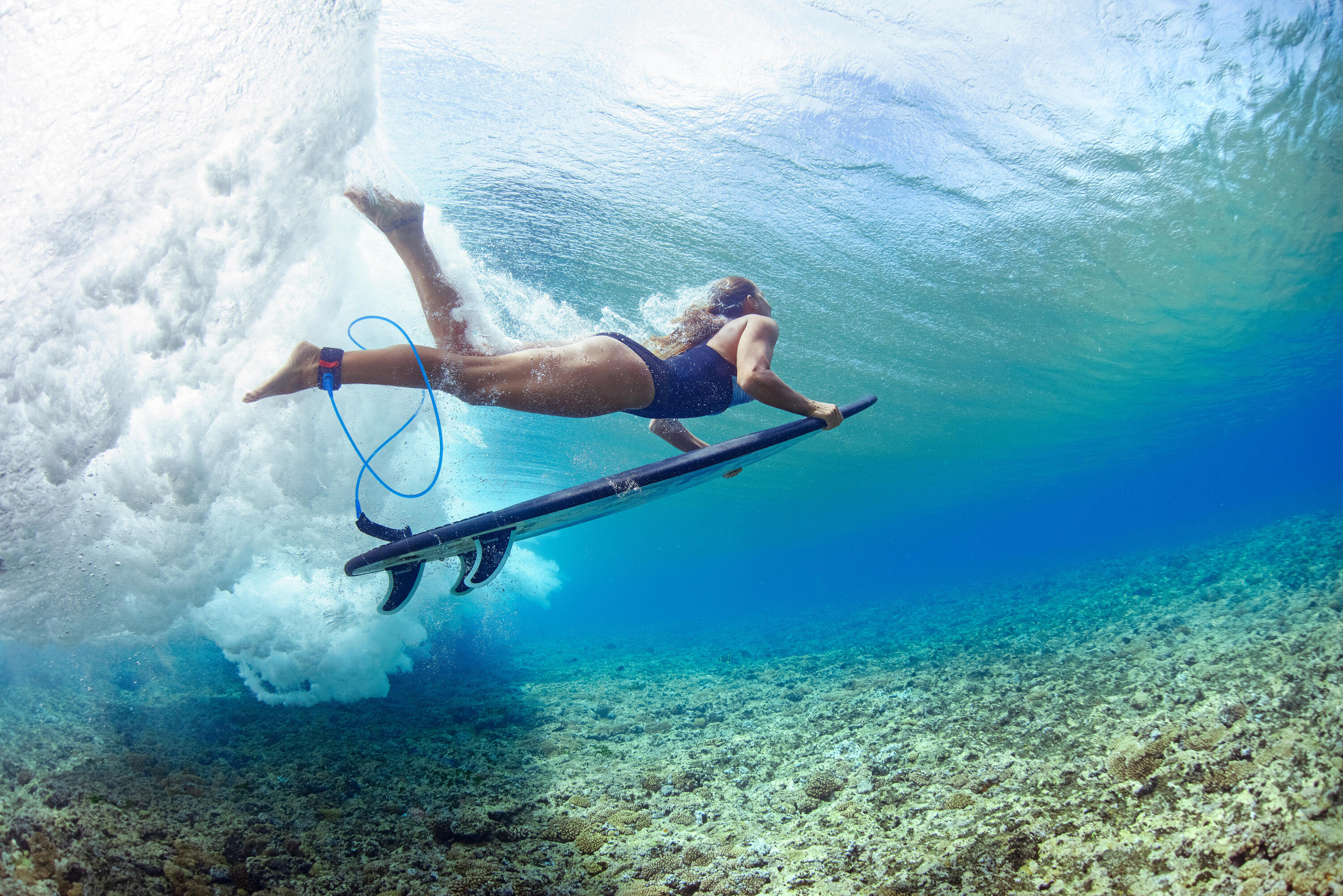 Frau macht einen Duck Dive unter einer Welle
