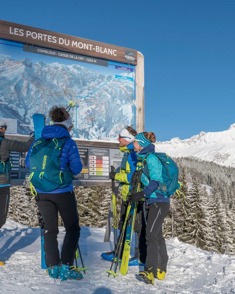 Skifahrer stehen vor Pistenschild von Les Portes du Mont-Blanc