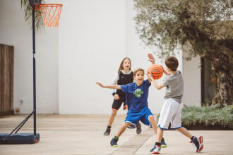 Enfants qui jouent au basketball devant la maison