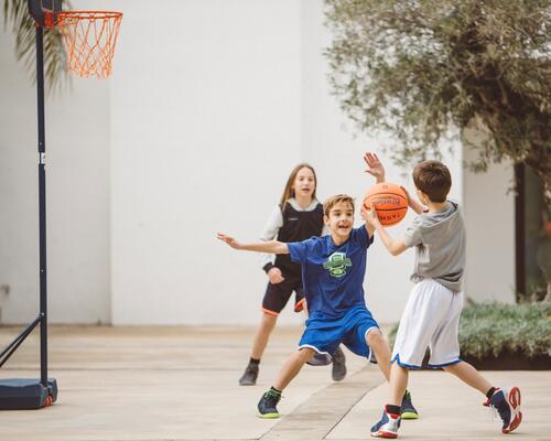 Enfants qui jouent au basketball devant la maison