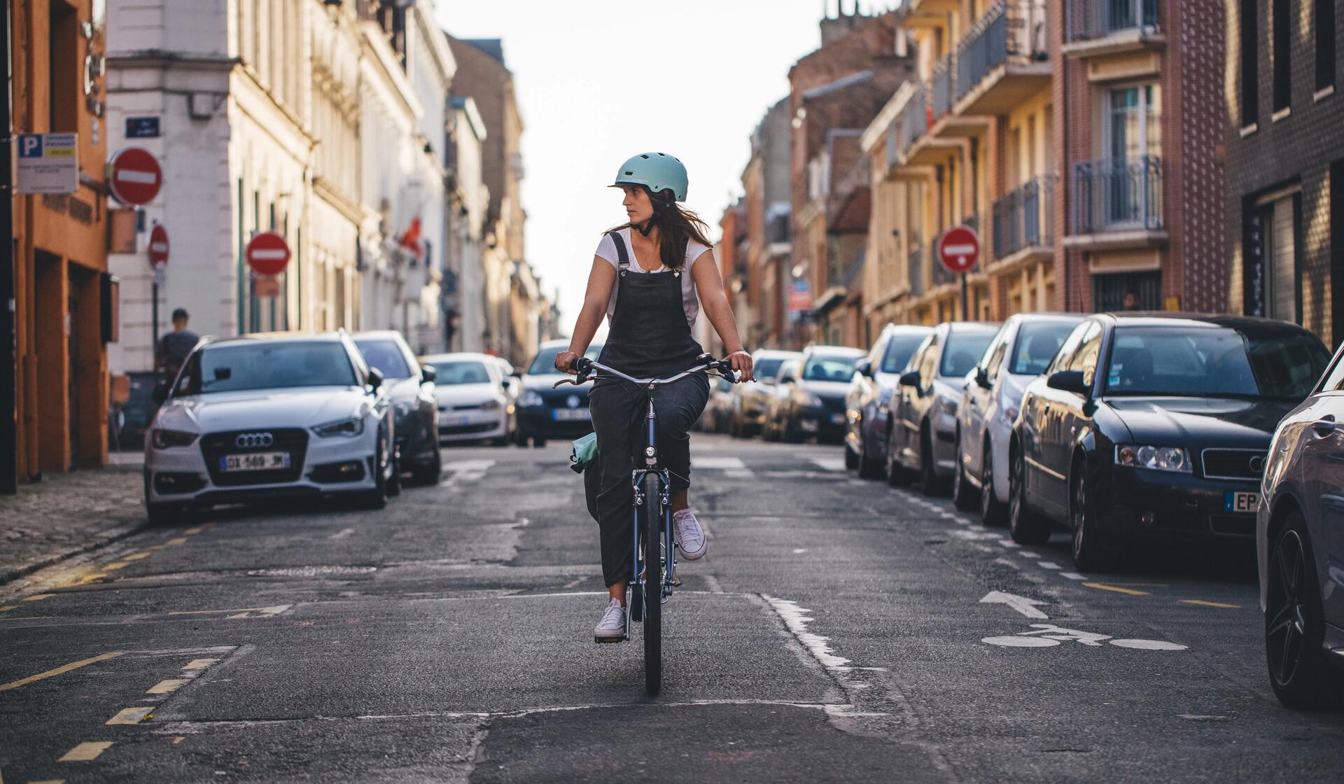 kobieta jadąca na rowerze ulicą w kasku 