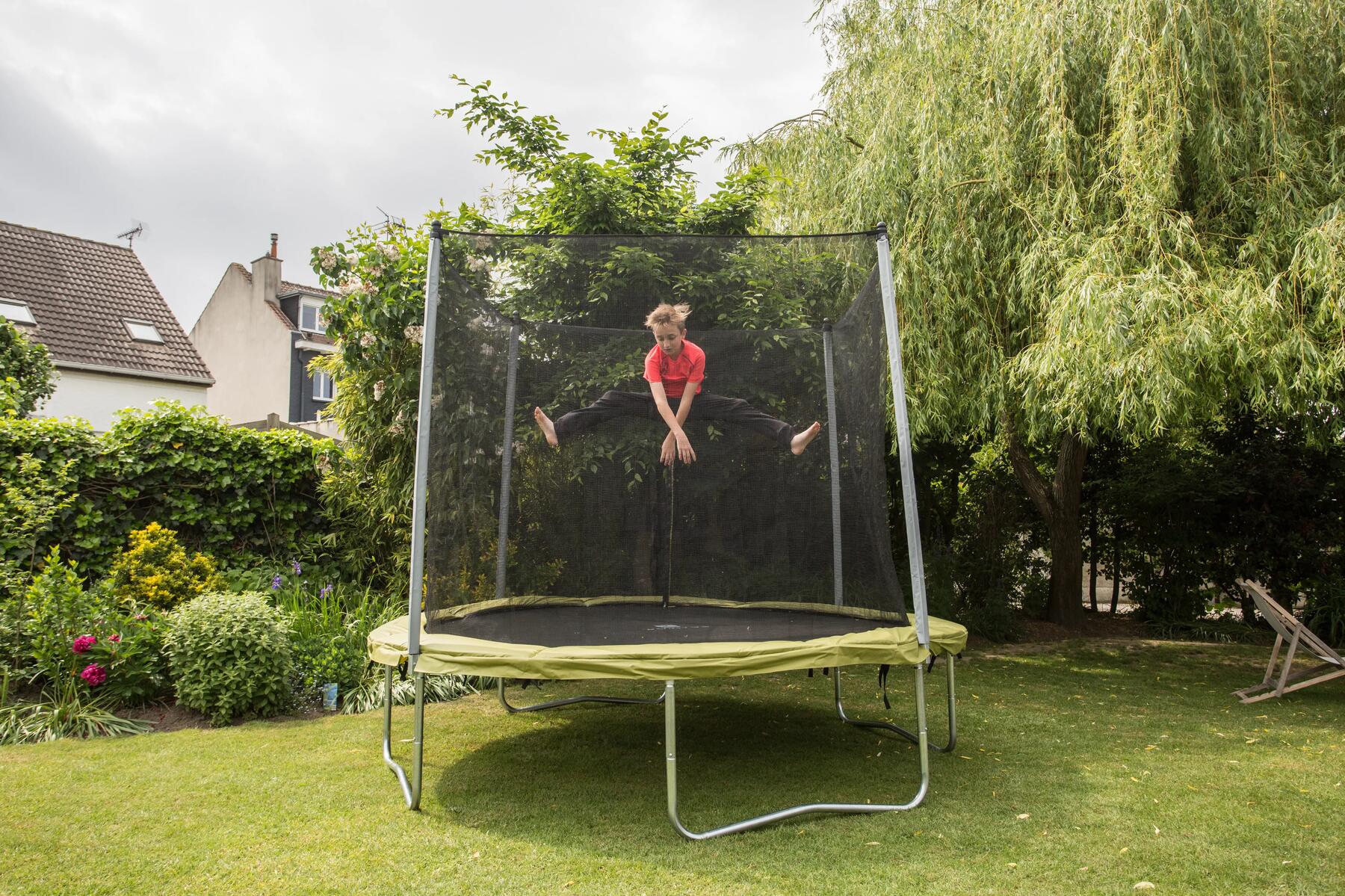 Ein Kind springt im Garten auf einem großen Trampolin