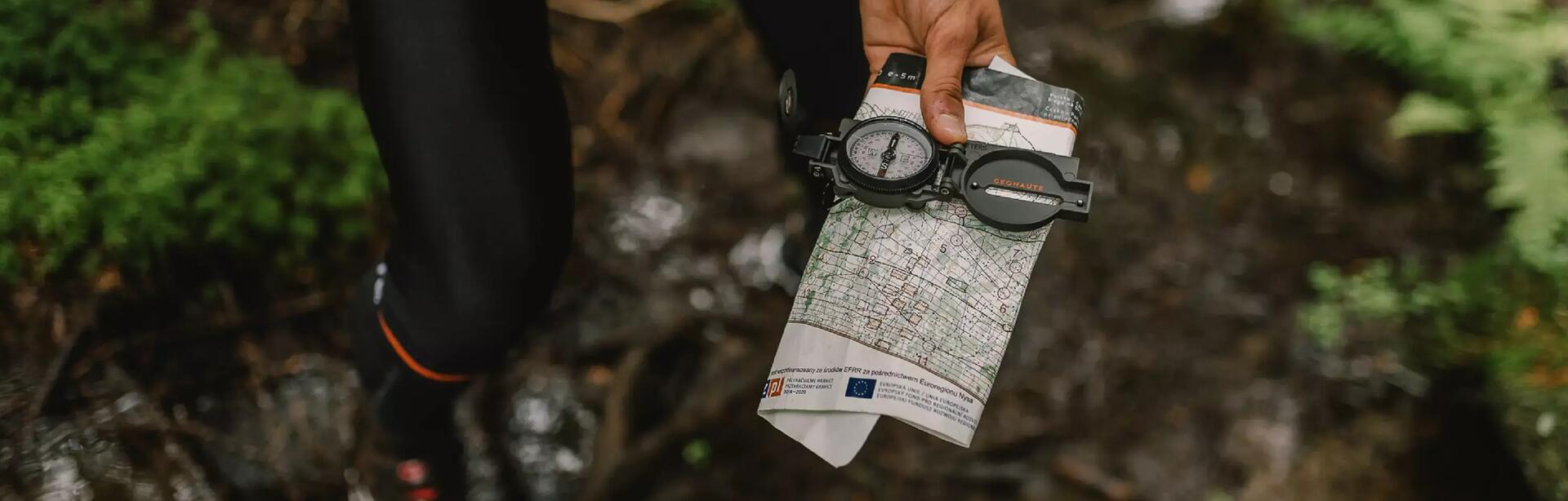 Man holding out a compass and map