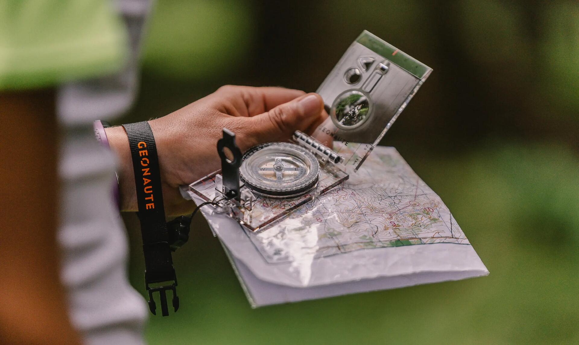 mężczyzna trzymający kompas turystyczny i mapę w dłoni 