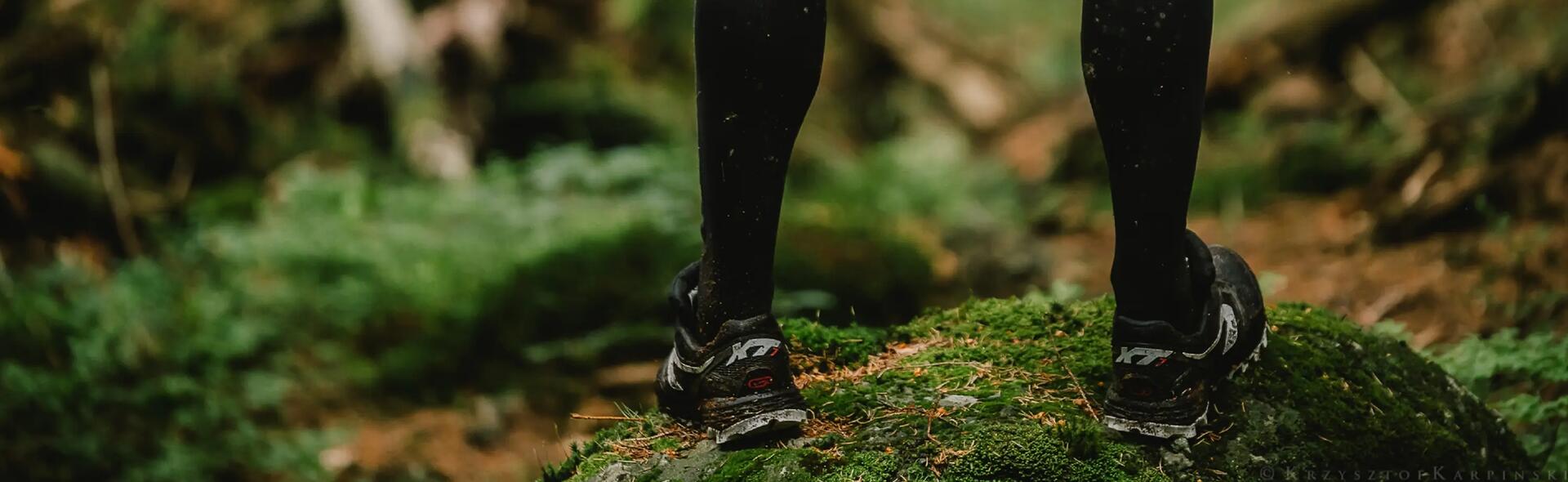 osoba stojąca w lesie  w butach do biegania po lesie 