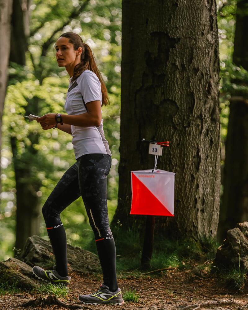 Eine Frau steht im Wald und hält eine Karte in der Hand.