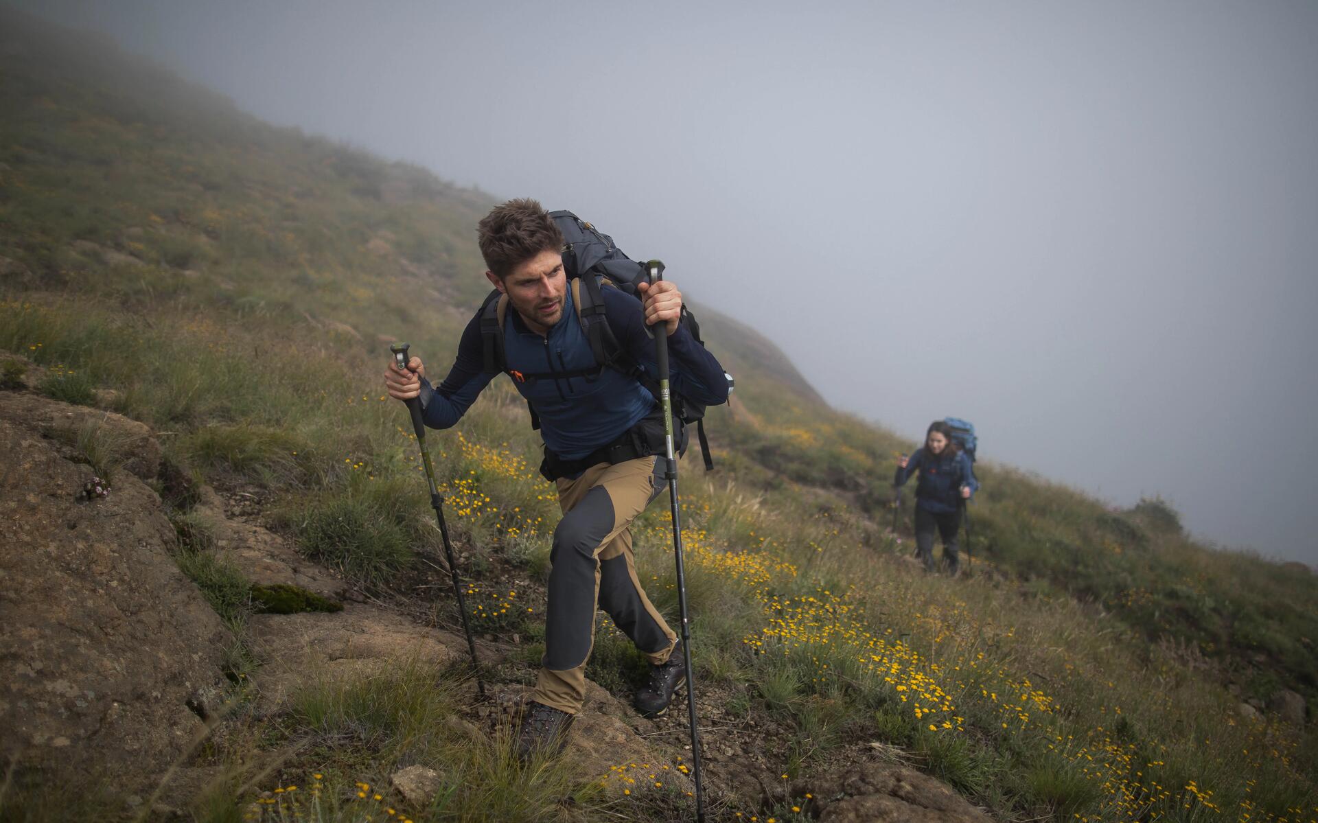 mężczyzna wędrujący po górach z kijkami trekkingowymi w rękach