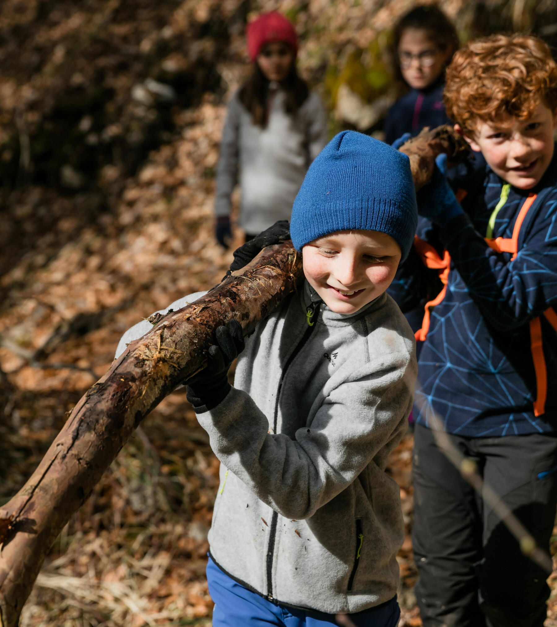 crianças a carregar um tronco de uma árvore decathlon