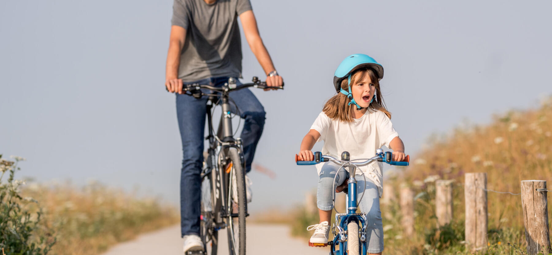 En vuxen och en flicka cyklar på en landsväg
