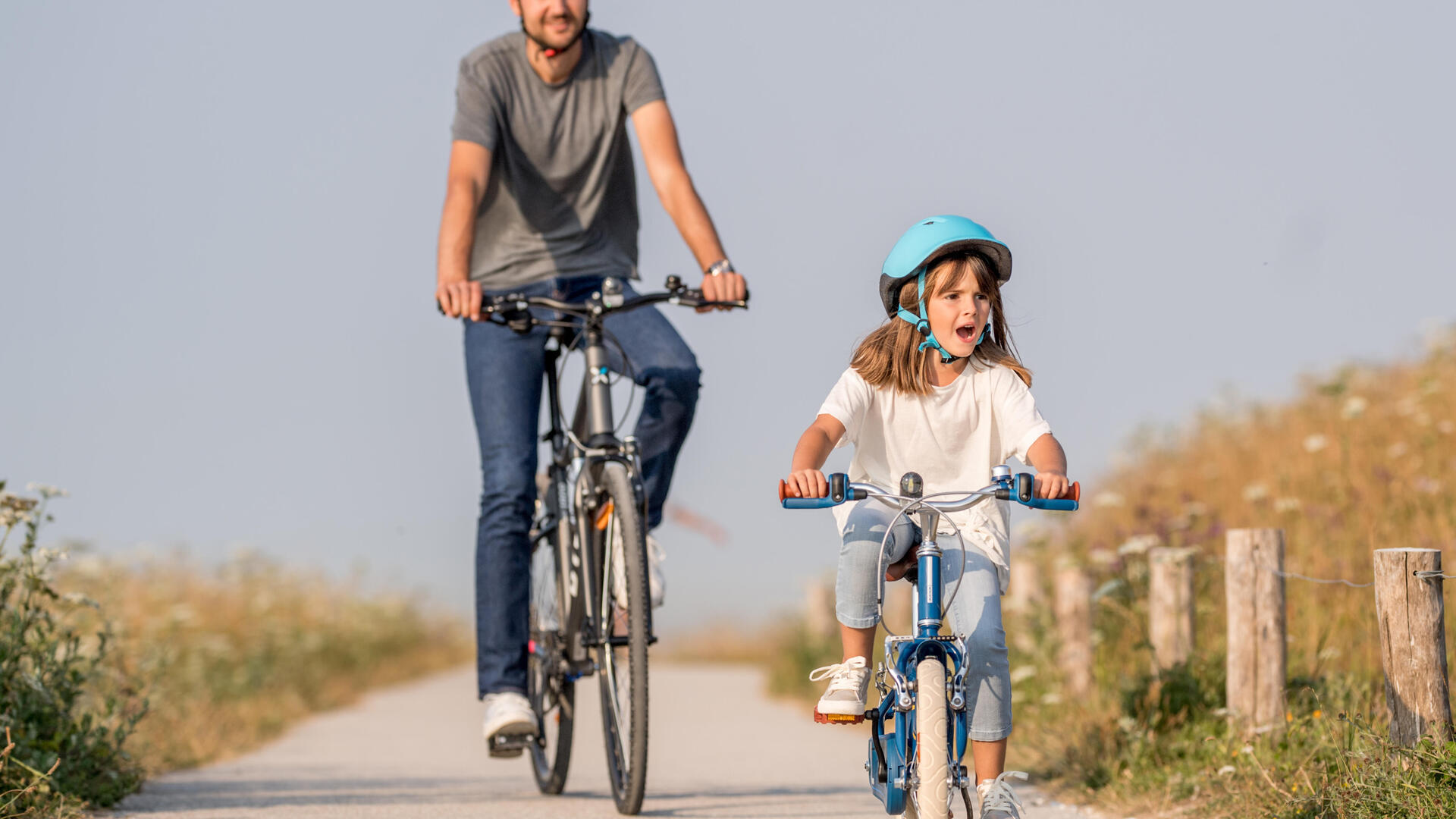 En vuxen och en flicka cyklar på en landsväg