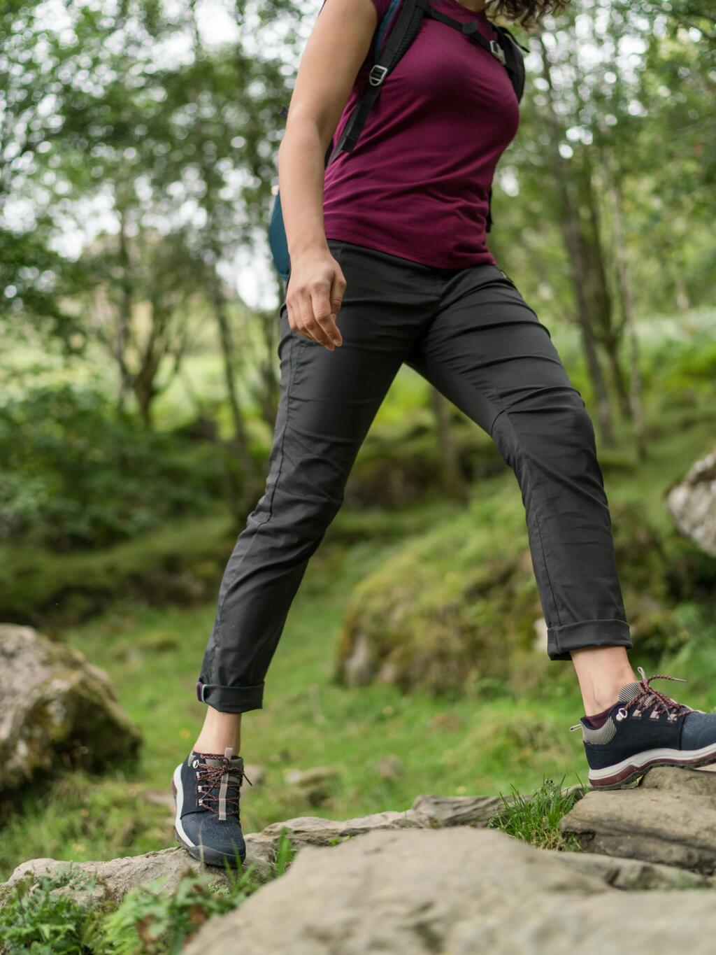 Ženska v temno sivih hlačah hodi po gozdu.