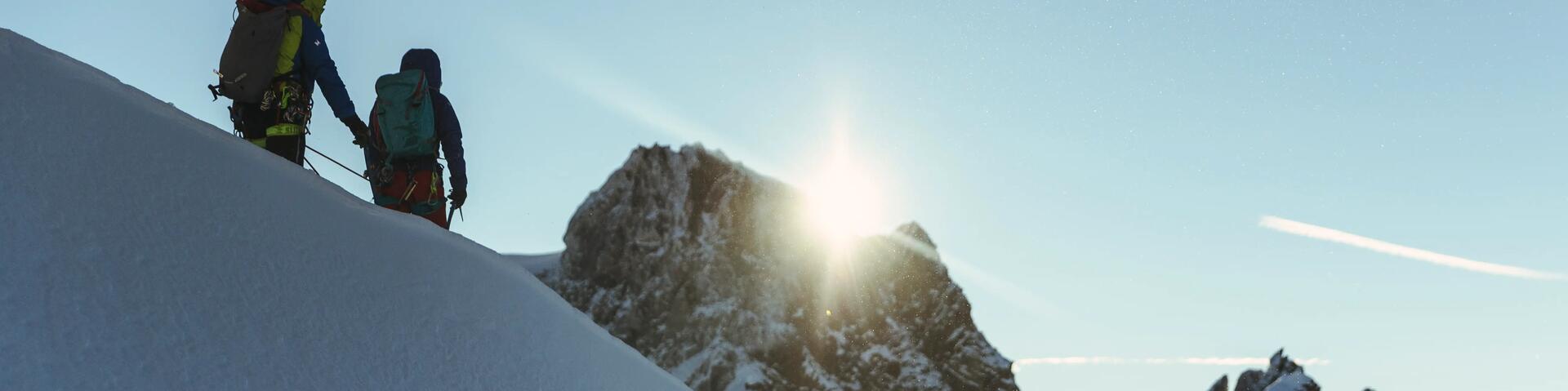 Two people hiking on a mountain with snow