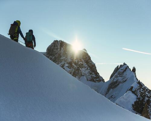 Two people hiking on a mountain with snow