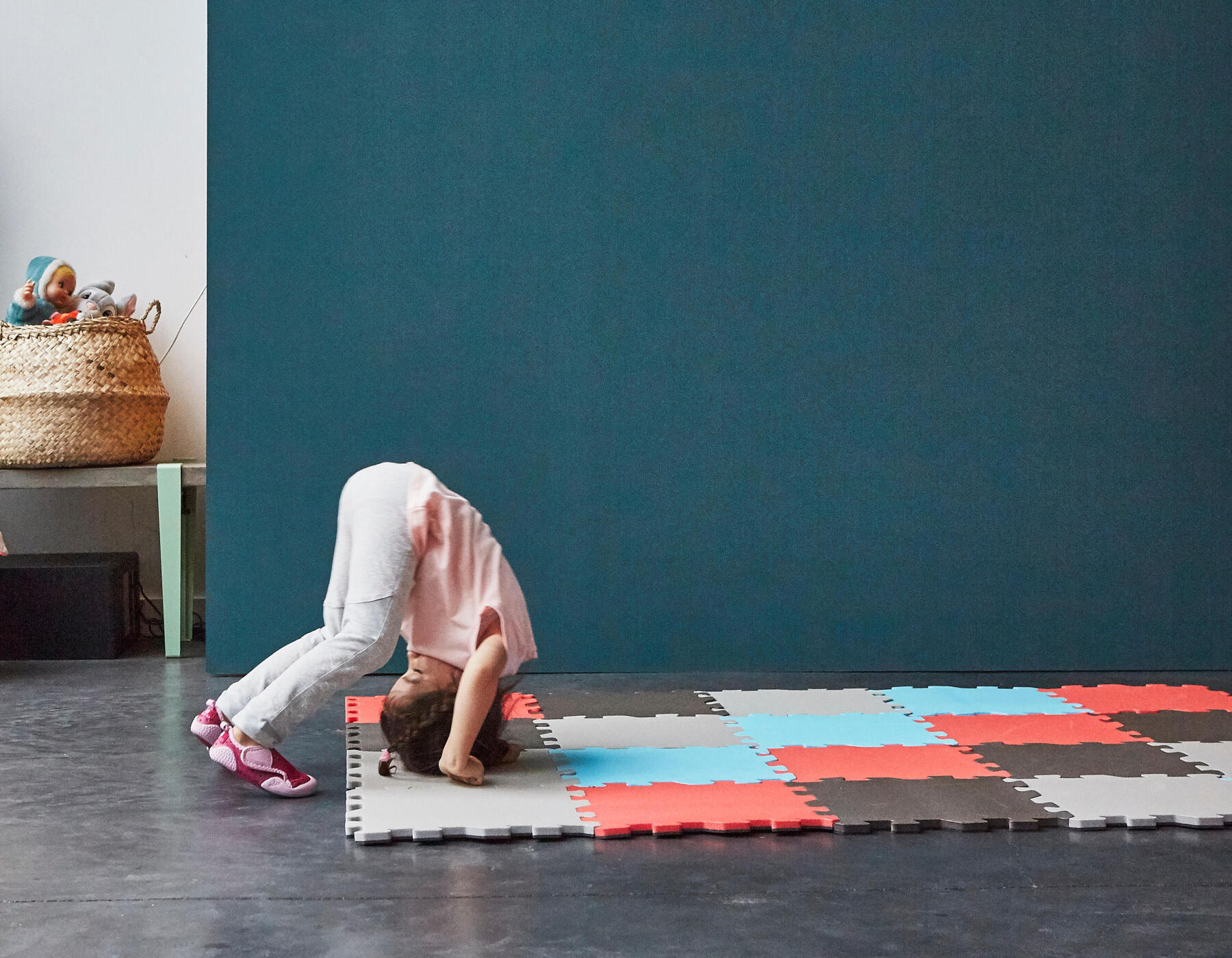 une petite fille qui s'apprête à faire une roulade sur un tapis de gymnastique