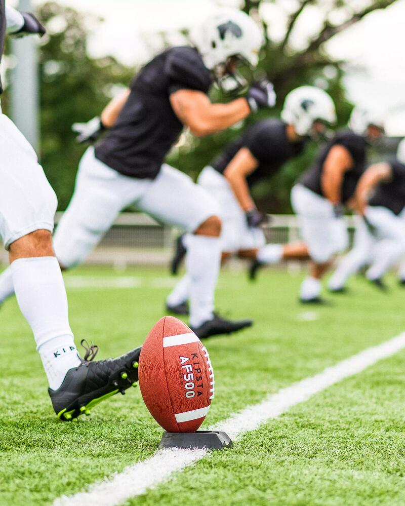 Viele Football Spieler setzen zum Sprint an und einer schießt den Ball.
