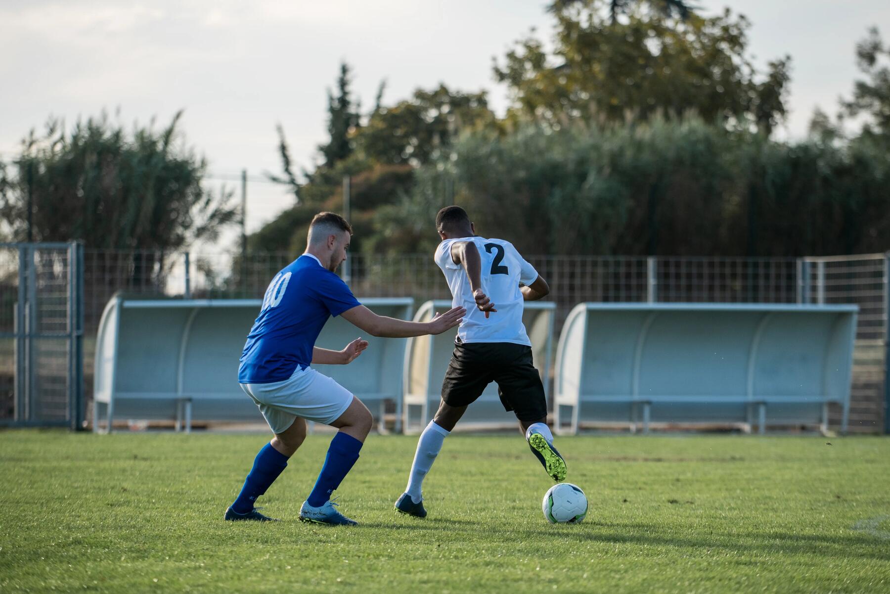 2 voetballers op een voetbalveld. 1 voetballer maakt een actie om de andere te passeren