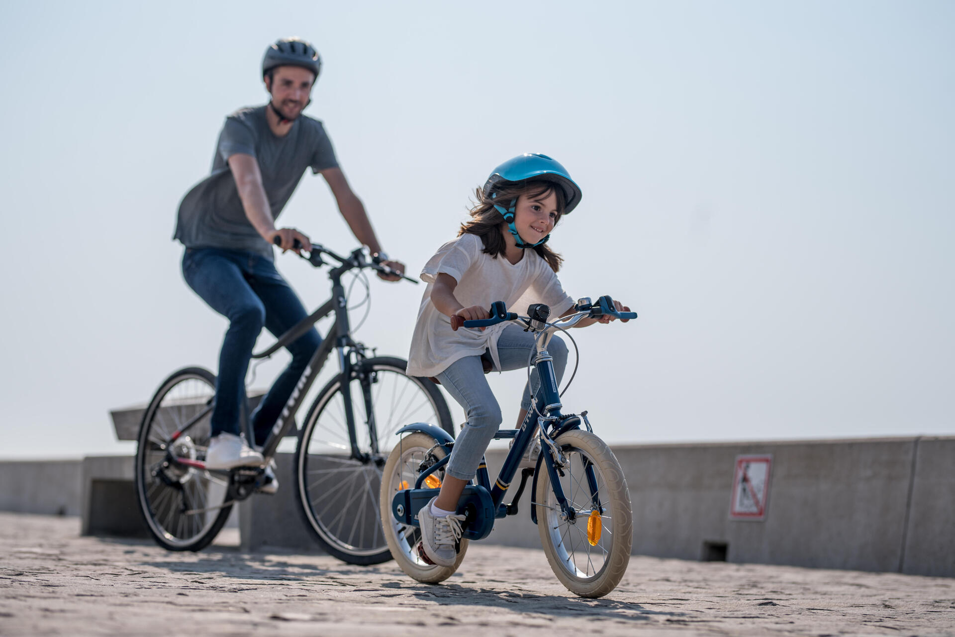 mężczyzna z dziewczynką jadą na rowerach w kaskach