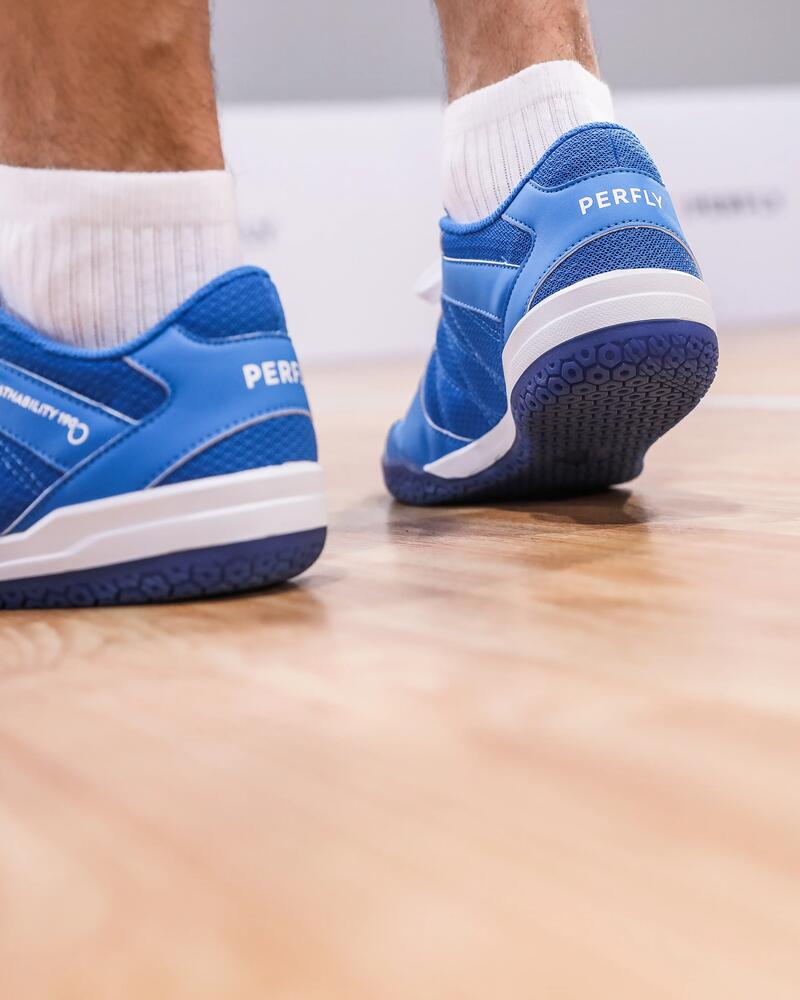 Die Füße eines Mannes, der blaue Badminton Schuhe trägt.