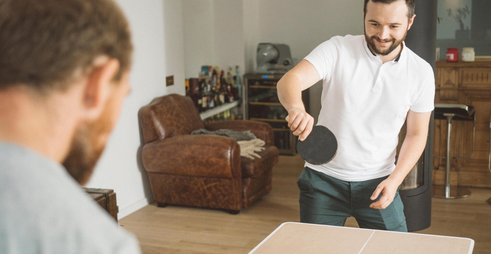 two men playing ping pong at home