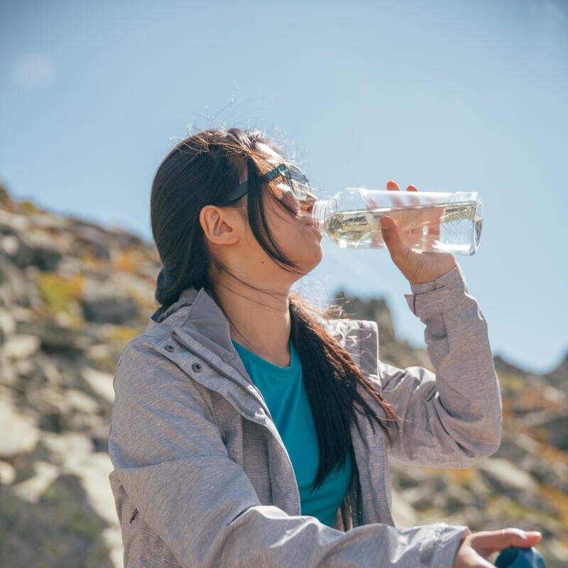 Mulher sentada a beber água  de um cantil após caminhada