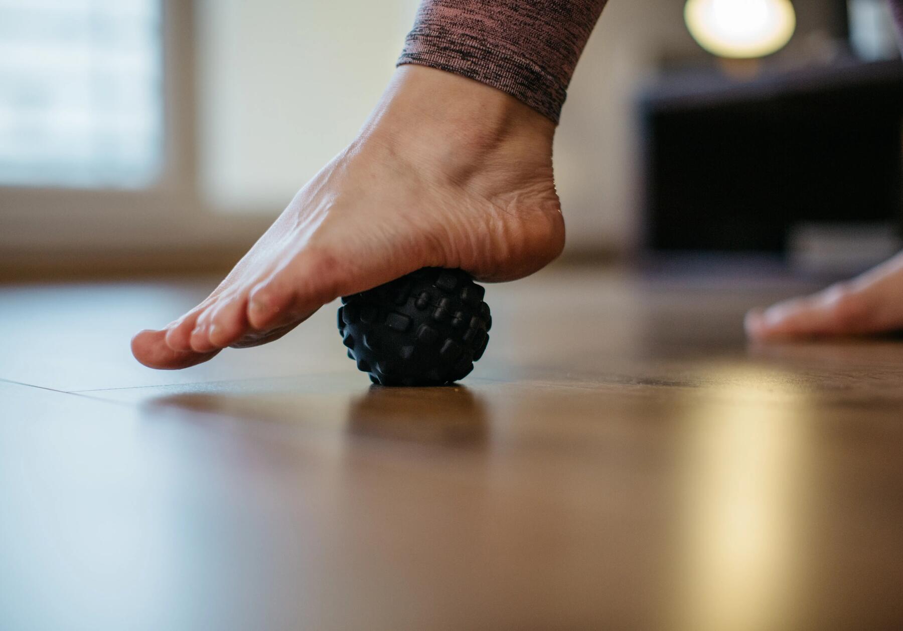 Kobieta używająca piłki do masażu stopy