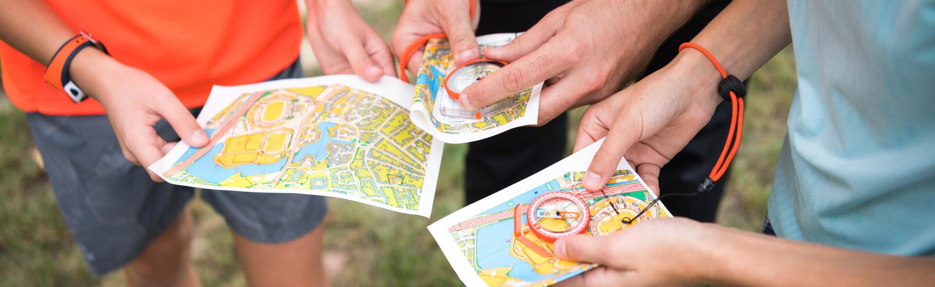 osoby trzymające mapy i kompasy turystyczne