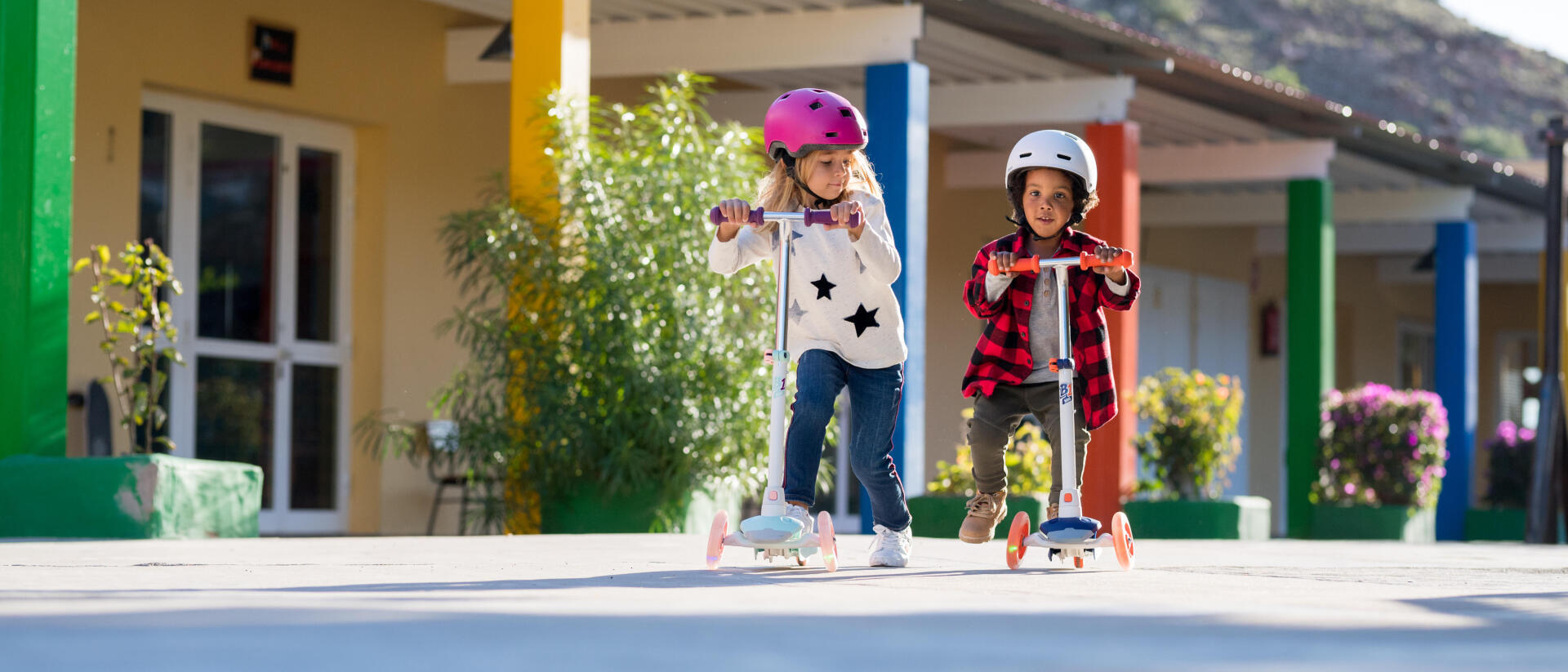 Duas crianças, menino e menina a andar de trotinete