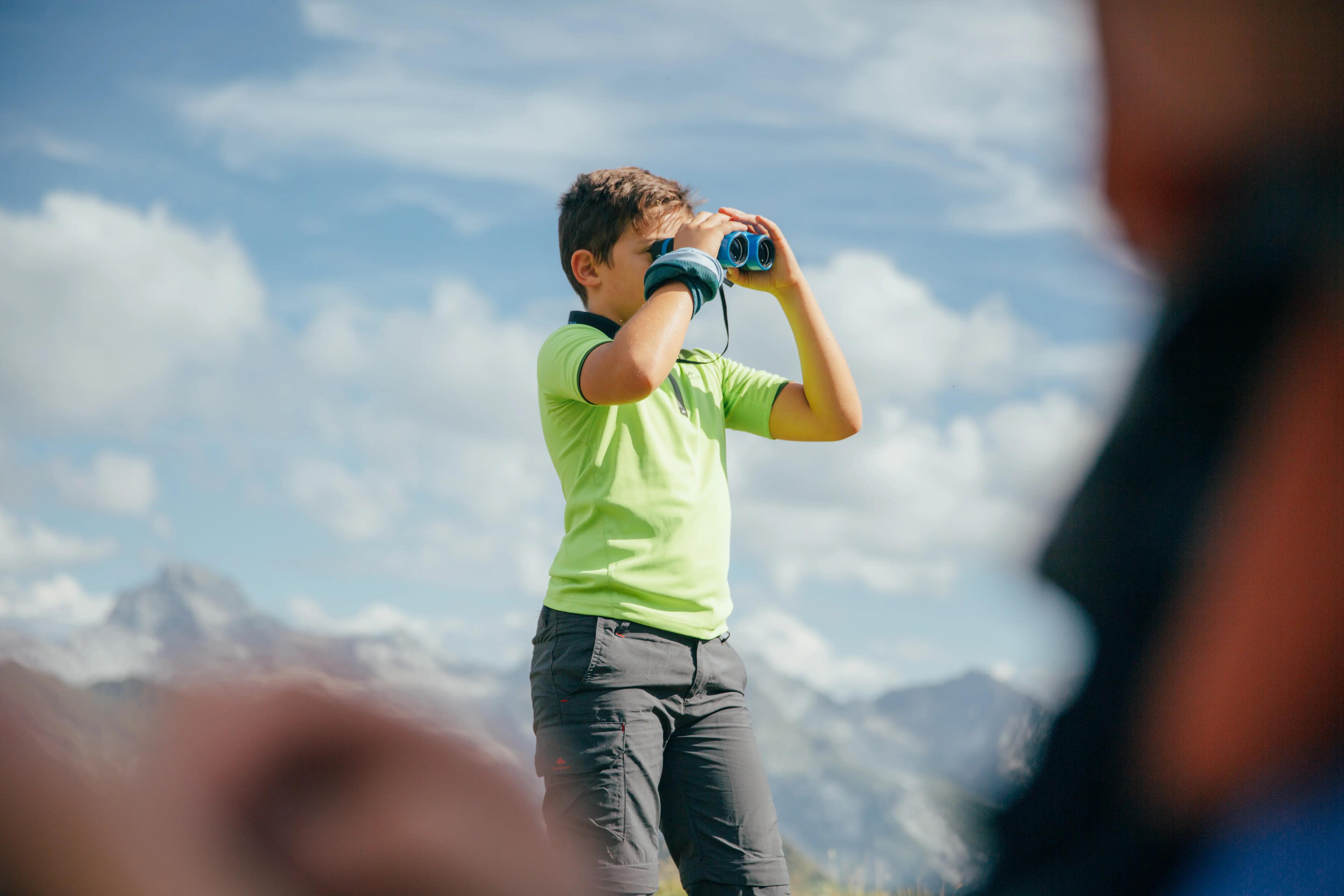 Child using binoculars while exploring a mountain landscape